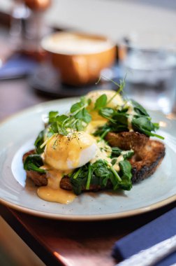 Healthy balanced breakfast with poached eggs, spinach and hollandaise sauce on toasted sourdough bread