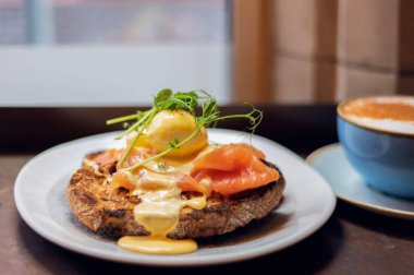 Healthy balanced breakfast with poached eggs, smoked salmon and hollandaise sauce on toasted sourdough bread