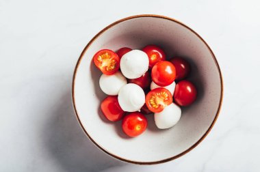 Preparation for Classic italian salad caprese served in original form with cherry tomatoes and mini mozarella pearls