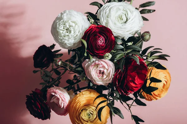 Fotokopi alanı olan pembe arkaplandaki vazodaki ranunculus çiçekleri. Çiçek aranjmanında bir demet İranlı düğün çiçeği.