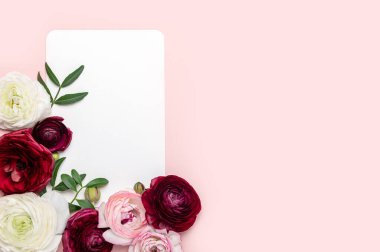 Fotokopi alanı ve boş kartı olan pembe arkaplandaki yumuşak ranunculus çiçekleri. Çiçek aranjmanında bir demet İranlı düğün çiçeği.