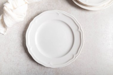 Beyaz seramik tabakta düz bir zemin üzerinde peçete var.