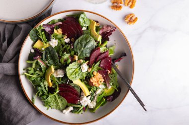 Yeşil Salata Yaprakları, Roket Salatası, Pancar Kökü Dilimleri, Avokado, Feta Peyniri, Ceviz ve Susam Tohumu 'ndan yapılmış sağlıklı salata.