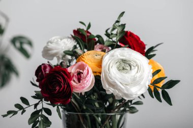 Vazodaki ranunculus çiçekleri beyaz arkaplanda fotokopi alanı ile birlikte. Çiçek aranjmanında bir demet İranlı düğün çiçeği