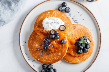Portakal reçelli taze Amerikan gözlemeleri, yabanmersini ve hindistan cevizli yoğurt, mükemmel kahvaltı.