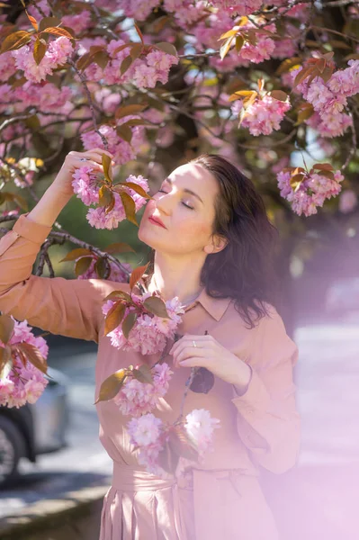 30 'lu yaşlarının ortalarında parkta çiçek açan kiraz ağacı ya da Sakura' lı bir kadın. İngiltere 'de ilkbahar. Hayatın ve güneşli havanın tadını çıkarıyorum.