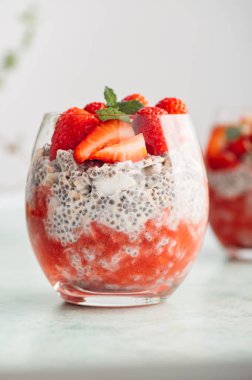 Badem sütü ve böğürtlen suyundan yapılmış taze çilekli bardaktaki sağlıklı chia pudingi. Güne sağlıklı başlamak için mükemmel bir kahvaltı.