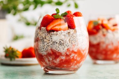 Badem sütü ve böğürtlen suyundan yapılmış taze çilekli bardaktaki sağlıklı chia pudingi. Güne sağlıklı başlamak için mükemmel bir kahvaltı.