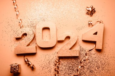 Altın parmaklar 2024. Parıltı ve kostüm süslemeleri de yakında. Tatil Partisi Dekorasyonu ya da kartpostal konsepti üst görünümü ve kopyalama alanı. 2024 yılının Şeftali Tüylü renginde