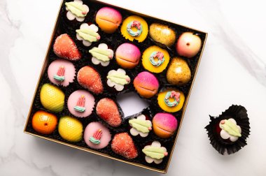 Bir kutu gökkuşağı badem ezmesi. Farklı meyve ve kekler şeklinde.