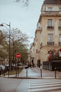 Paris, France - March 30, 2024: Parisian street in the morning during early spring and gloomy rainy day. Toned image clipart