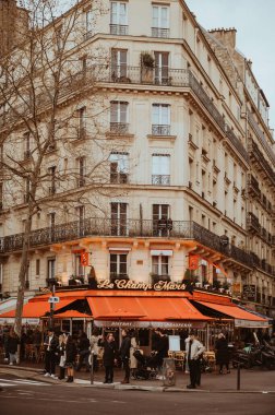 Paris, Fransa - 30 Mart 2024: Paris caddesi ve kafe dolusu turist bahar başlarında ve kasvetli yağmurlu bir günde. Tonu ayarlanmış resim