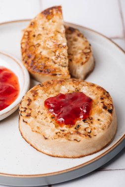 Çilek reçelli bir tabakta tereyağlı sıcak kızarmış hamur tatlısı. Mükemmel lezzetli kahvaltı İngiltere 'de popüler.