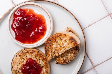Çilek reçelli bir tabakta tereyağlı sıcak kızarmış hamur tatlısı. Mükemmel lezzetli kahvaltı İngiltere 'de popüler.