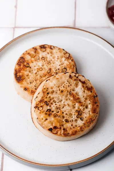 stock image Hot Toasted Crumpets with on a plate with strawberry jam nearby. Perfect tasty breakfast