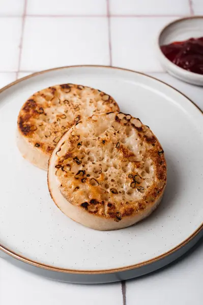 stock image Hot Toasted Crumpets with on a plate with strawberry jam nearby. Perfect tasty breakfast