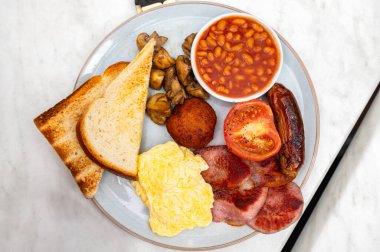 Sosis, mantar, domates, pastırma, ev yapımı haşlanmış et, fasulye, çırpılmış yumurta ve tereyağlı ekmek ile tam İngiliz kahvaltısı.