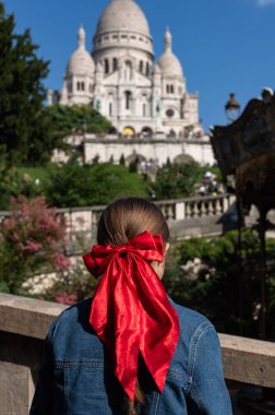 Saçında kırmızı kurdele olan turist kız Paris 'te Sacre-Coeur Bazilikası olarak bilinen Sacre Coeur de Montmartre Bazilikası' nı izliyor.