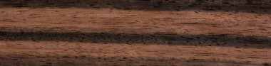 Malabar abanoz ağacından bir yüzeyin yakın görüntüsü koyu ve zengin bir rengi ve pürüzsüz bir dokusu var. Tahtanın ince ve düzgün bir tahıl deseni ve parlak bir sonu var.