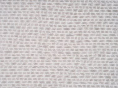 Bir tasarımcı, yükseltilmiş ızgara benzeri bir yapıya sahip açık gri kaplama yüzeyi, derinlik ve karmaşıklık hissi verir.