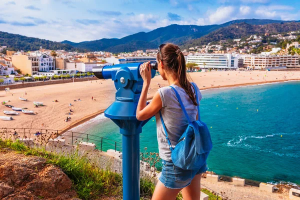 Tourist woman in Badia bay in Tossa de Mar in Girona, Catalonia, Spain near of Barcelona. Ancient medieval castle with nice sand beach and clear blue water. Famous tourist destination in Costa Brava