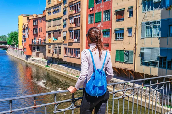 観光客の女性は ジローナ カタルーニャ スペインのカラフルな赤と黄色の家と橋の川オニヤールに見ます 風光明媚な古代の町 有名な観光地の目的地は 休日や休暇のための完璧な場所 — ストック写真