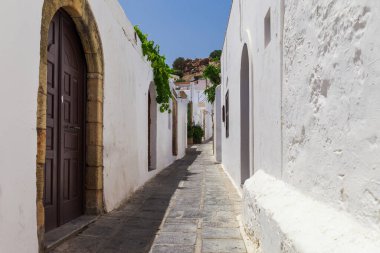 Rodos adasında Lindos kasabasında Dar sokak, Oniki, Yunanistan. Çiçeklerle güzel doğal eski eski beyaz evler. Güney Avrupa'nın ünlü turistik beldesi