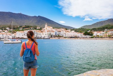 Tourist woman in Cadaques, Catalonia, Spain near of Barcelona. Scenic old town with nice beach and clear blue water in bay. Famous resort destination in Costa Brava with Salvador Dali landmark clipart