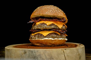 Lokantalar için koyu bir geçmişi olan ahşap bir tahtanın üzerinde sulu, duble pastırmalı çizburger..