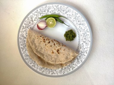 Geleneksel adıyla Marathi 'de Theccha ve tabağın yanında taze soğan olarak adlandırılan yeşil biberli Hint düz ekmeği. Bir Maharashtrian yemeği..