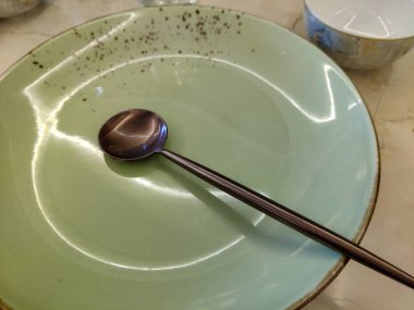 Restoranda yeşil bir tabağın ve kahverengi kaşığın en üst görüntüsü.