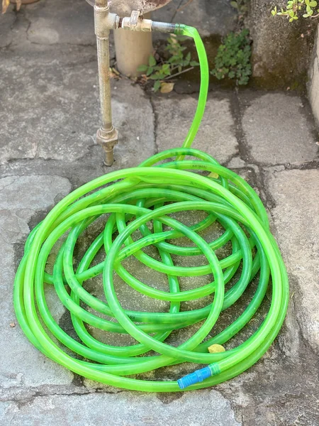 Closeup of green water hose pipe connected to water tap.