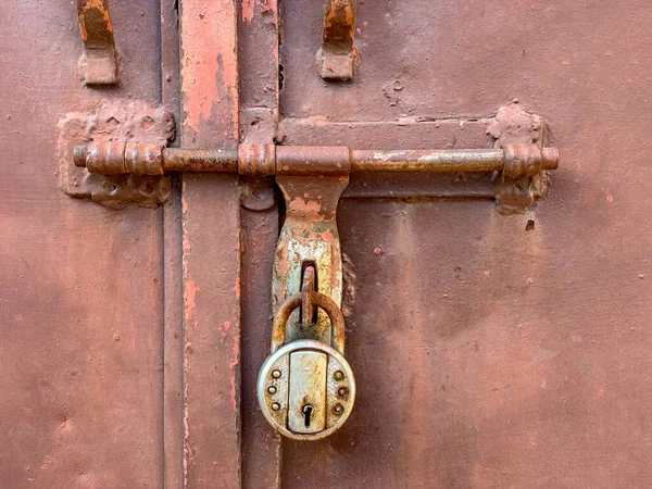 A brown rusted closed door with a lock closeup horizontal