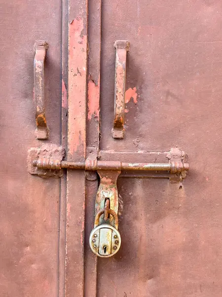 A brown rusted closed door with a lock closeup vertical