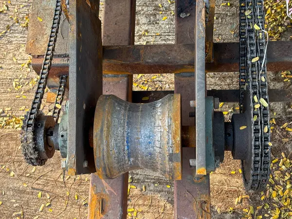 Close-up of a rusty industrial chain and sprocket, with blurred background, depicting machinery, aging, and wear.