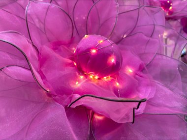 Peri ışıklarıyla suni pembe çiçeklerin yakın plan görüntüsü. Kasımpatı beyaz sarı ışık.