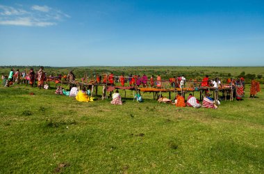A lively outdoor Maasai market with colorful garments and goods on display against a natural backdrop clipart