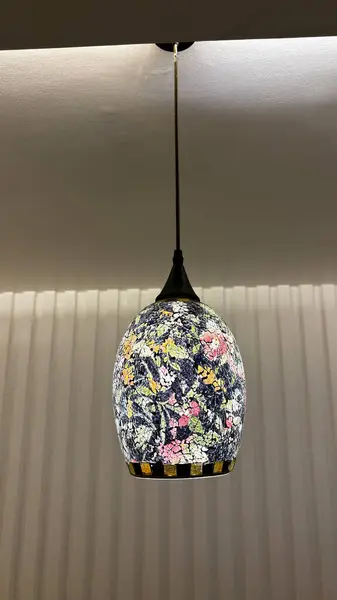 A light fixture with a floral design is hanging from the ceiling. The light is on and the room is illuminated