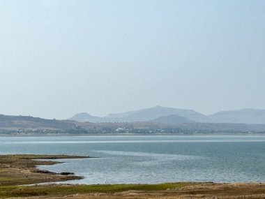 Arka planda dağ olan sakin bir göl. Gökyüzü açık ve mavi. Su durgun ve huzurlu Gangapur Barajı Nashik Hindistan Mart-2024