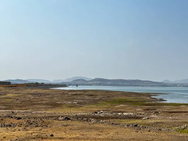 Arka planda dağ olan sakin bir göl. Gökyüzü açık ve mavi. Su durgun ve huzurlu Gangapur Barajı Nashik Hindistan Mart-2024