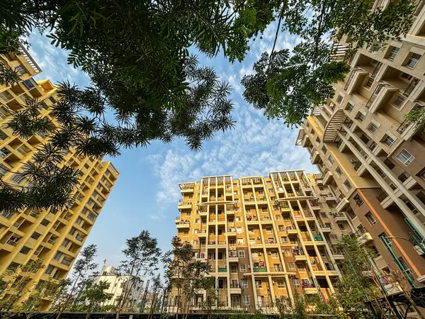 Wide angle view of apartment buildings surrounded by trees with blue sky in the background.