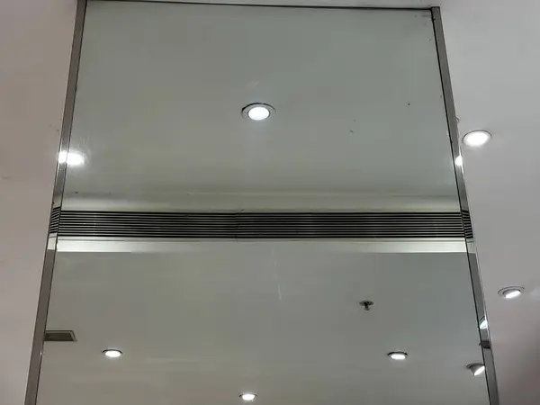 The ceiling is white and has a few lights. The room is very bright and clean and having mirror.