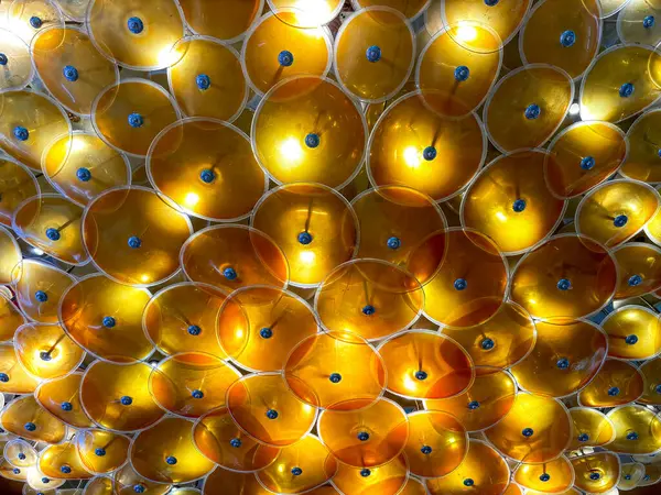 A close up of a yellow and blue light fixture. The light fixture is made of many small, round pieces of glass