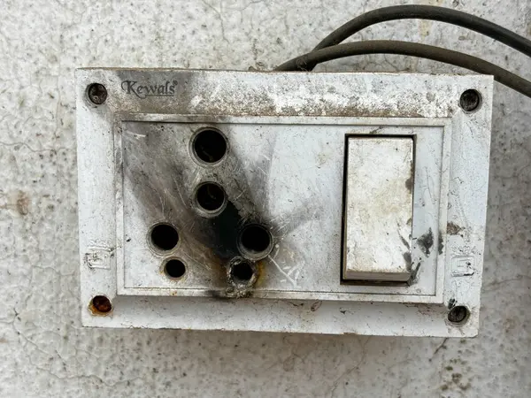 A burnt out electrical box with a keyval brand name on it. The box is dirty and has a burnt out light
