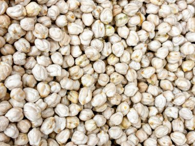 Bir porsiyon beyaz nohut. Görüntü büyük bir nohut yığınına ait, bazıları diğerlerinden biraz daha büyük. Yığınlar yayılmış ve çeşitli boyutlarda.