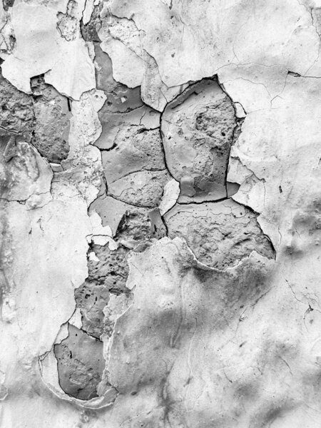 Трещина и сломанная стена с несколькими кусочками красной краски. Стена выглядит старой и изношенной.