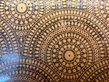 Merkezinde bir çember olan desenli bir arka plan. Çember daha küçük dairelerle çevrili. Arka plan kahverengi ve daireler beyaz.