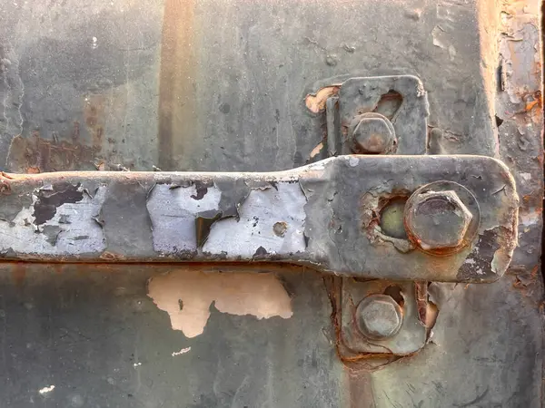 A rusty bolt is attached to a metal object. The bolt is rusted and has a few holes in it