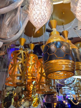 Tavandan sarkan altın ve siyah ışık armatürleri koleksiyonu. Eşyalar çeşitli şekil ve boyutlarda ve hepsi tavandan sarkıyor.