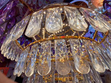 Üzerinde bir sürü cam parçası olan büyük bir avize. Avize altındır ve içinden çok fazla ışık gelir.